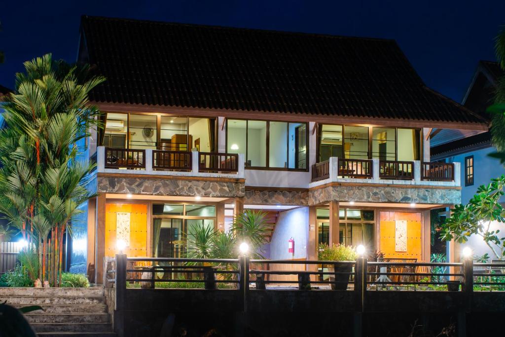 una casa con balcón por la noche en BaanRimNam Resort Trat, en Trat