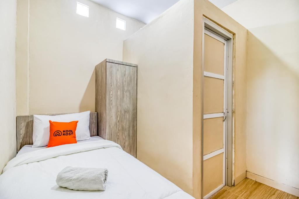 a small bedroom with a bed with an orange pillow at KoolKost near ISI Yogyakarta (with minimum stay applies) in Yogyakarta