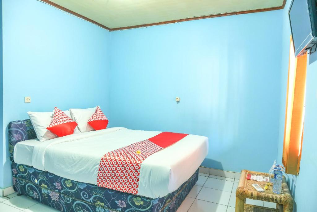 a blue room with a bed with red pillows at OYO 1662 Zury Homestay in Kuta Lombok