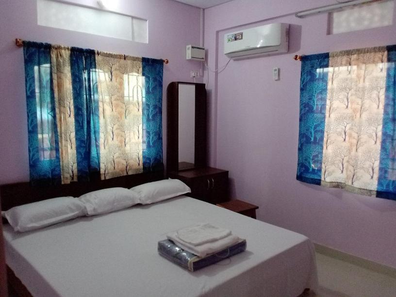 una camera da letto con un grande letto con due finestre di Sunrise Home Stay a Port Blair