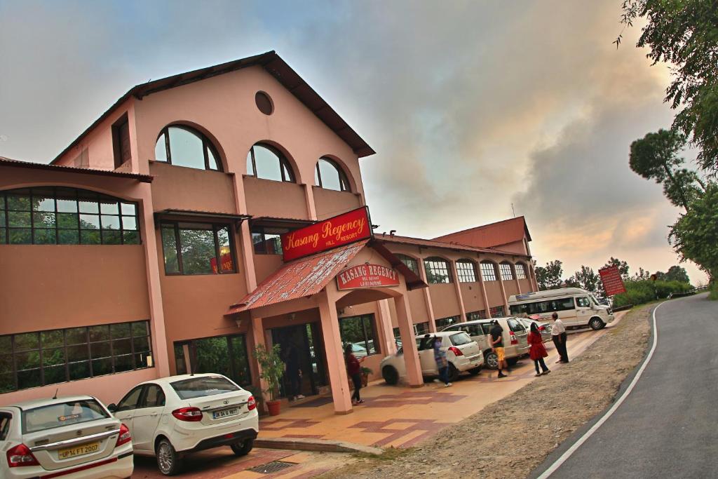 a large building with cars parked in front of it at Kasang Regency Hill Resort in Lansdowne