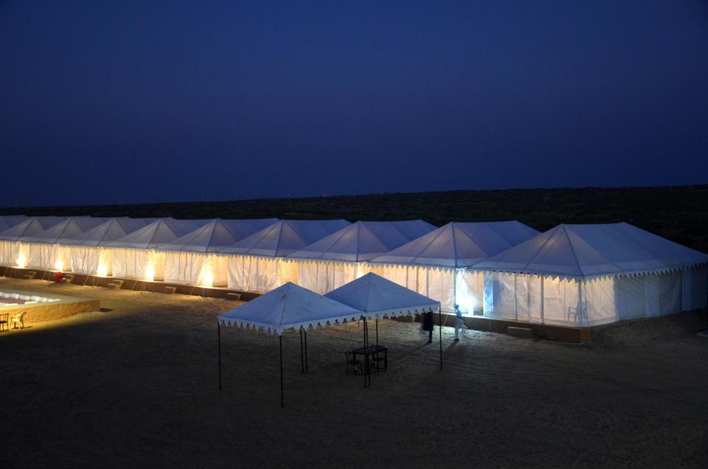 a row of white tents in the desert at night at Sky Desert Safari in Sām