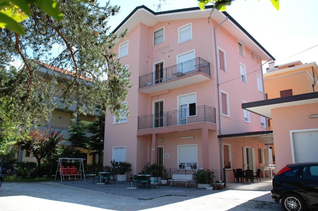 ein rosafarbenes Gebäude mit Tischen und Stühlen davor in der Unterkunft Villa Linda Affittacamere in Bellaria-Igea Marina