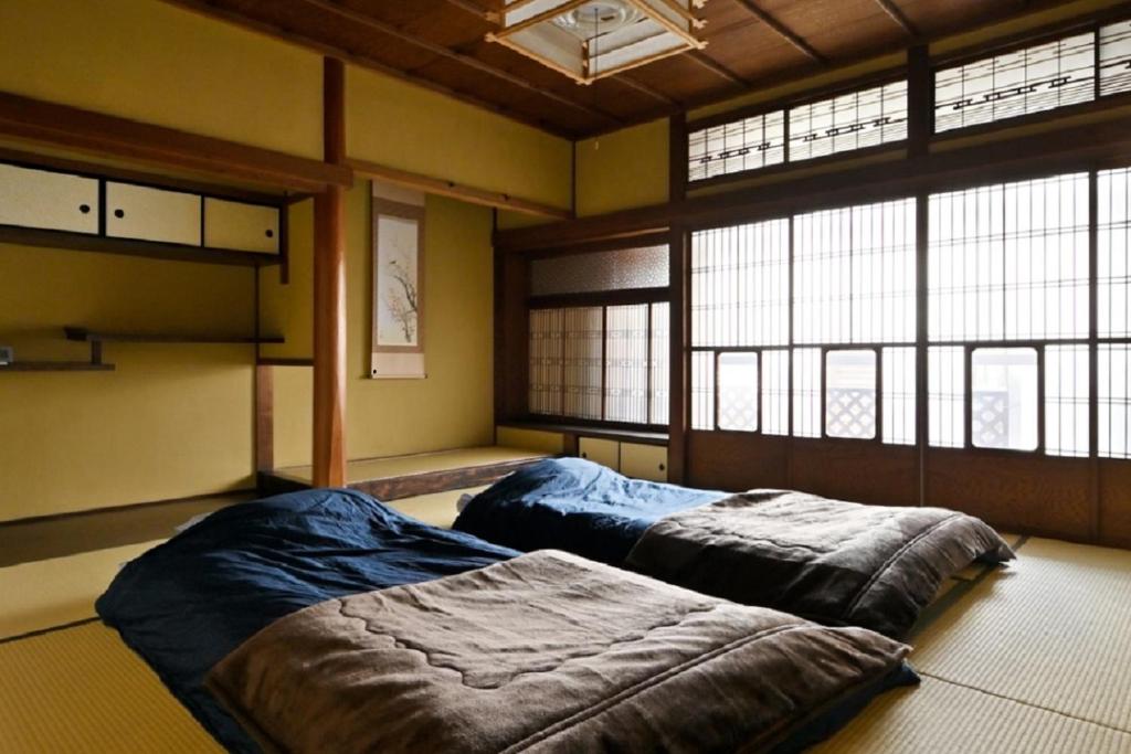 Yuzan apartment Sanjo في نارا: سريرين في غرفة كبيرة مع نوافذ