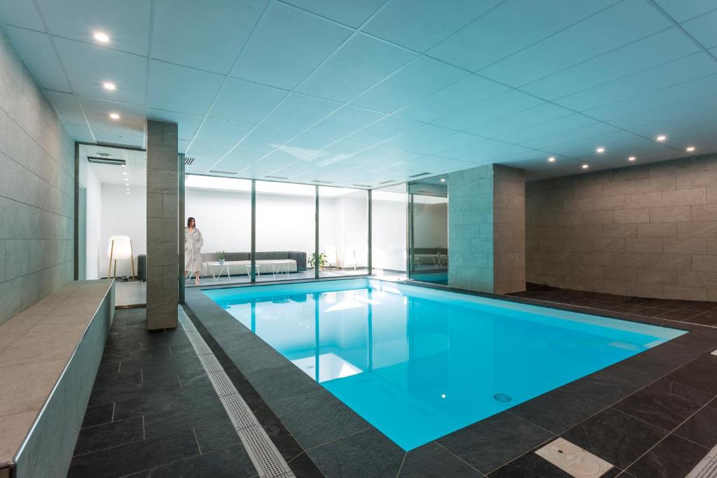 a swimming pool in a building with a person in the background at Nemea Appart Hotel So Cloud Lyon Gare Part-Dieu in Lyon