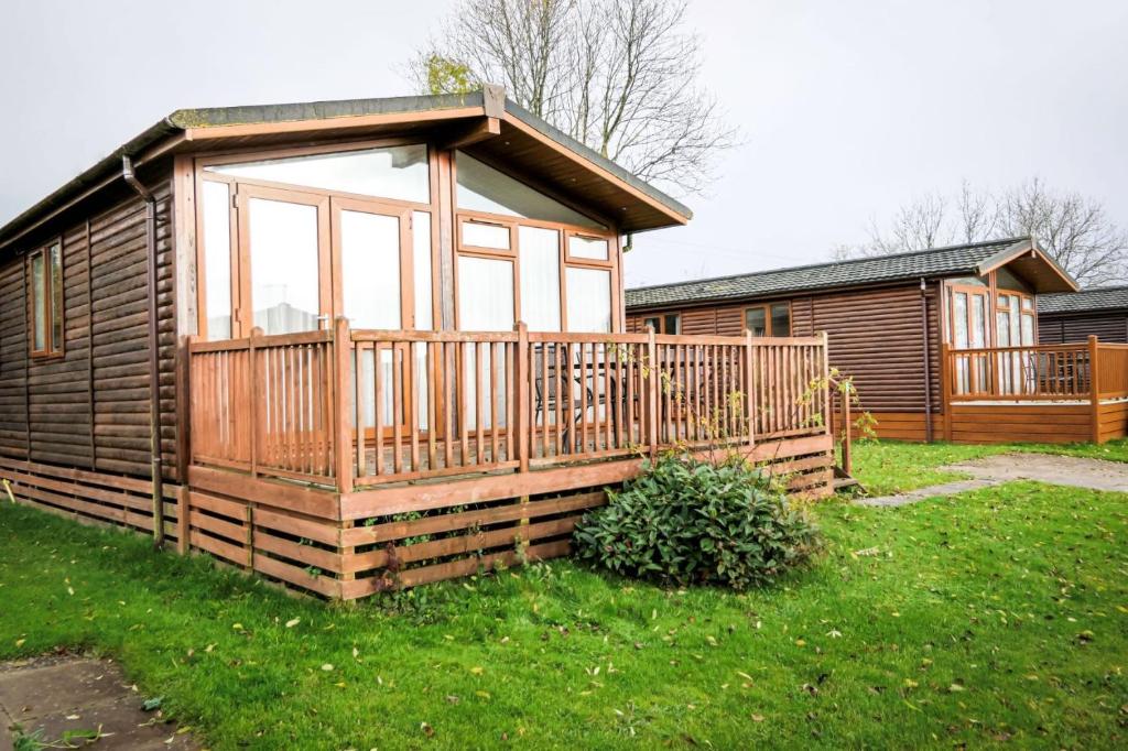 a wooden cabin with a large window in the grass at Dove Lodge Ashbourne Heights in Ashbourne