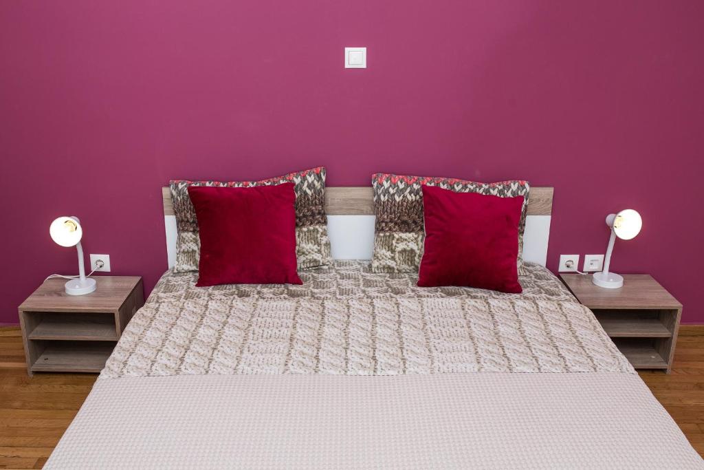 Dormitorio púrpura con cama con almohadas rojas en Voula's Apartment en Atenas
