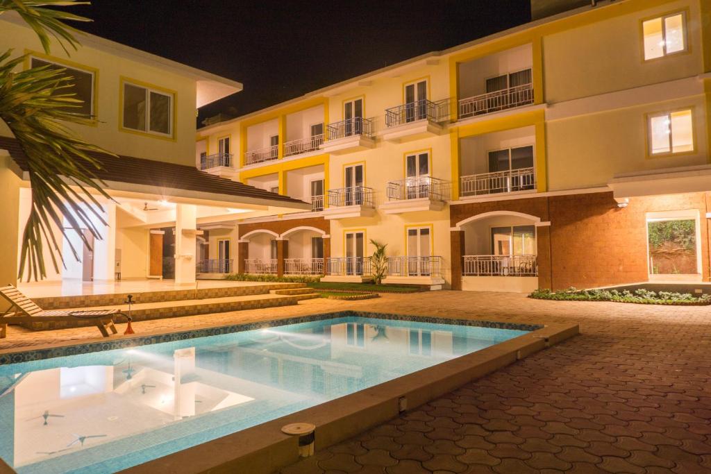 a swimming pool in front of a building at night at Passions de Goa in Anjuna