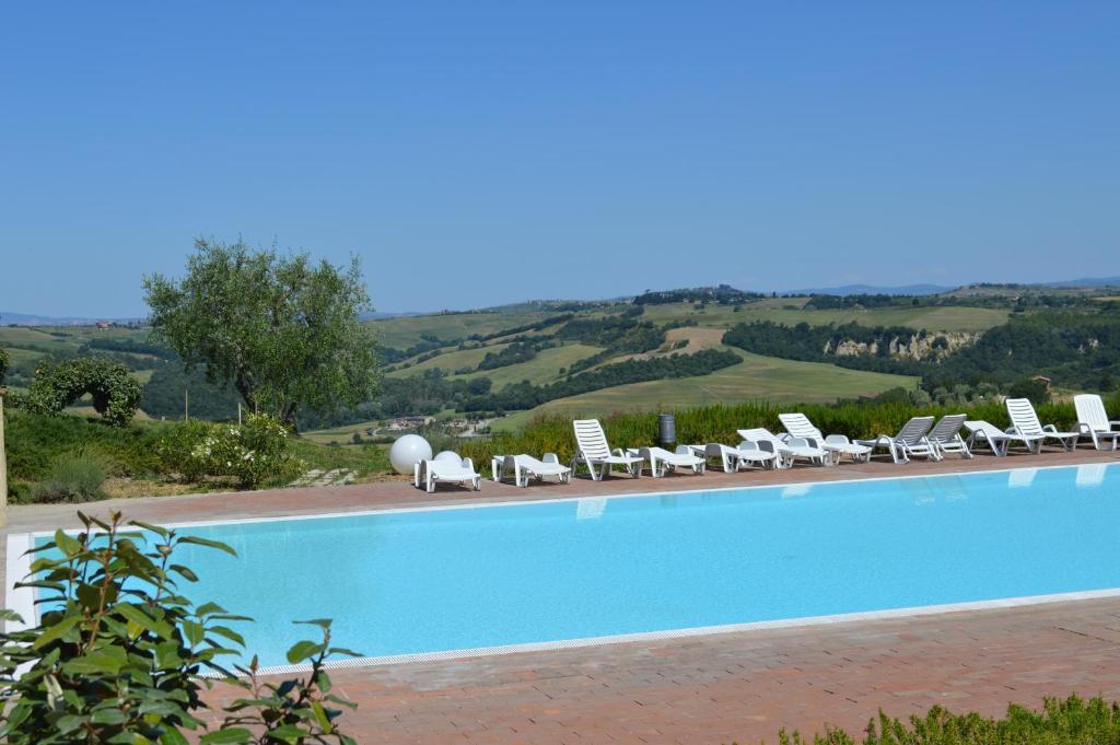 a large swimming pool with lounge chairs and a view at Monaci Apartments in Asciano