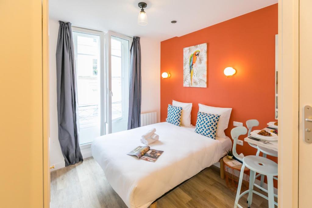a bedroom with a bed with an orange wall at Apartments WS - Haut-Marais - Carreau du Temple in Paris