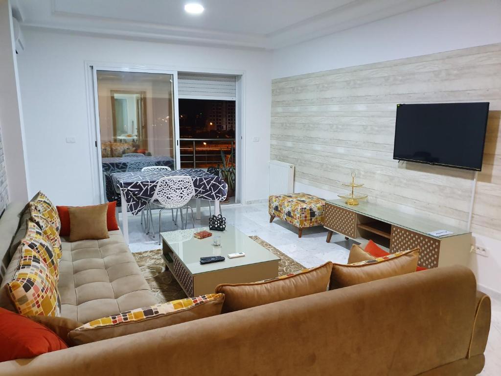 ein Wohnzimmer mit einem Sofa und einem TV an der Wand in der Unterkunft Luxury and Splendid 2 Bedrooms Apartment in Jardin De Carthage Tunis in Tunis