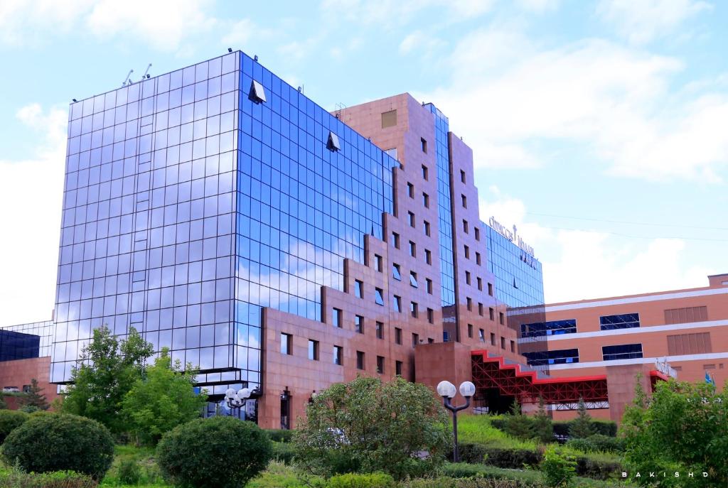 a tall glass office building in a city at Chinggis Khaan Hotel in Ulaanbaatar