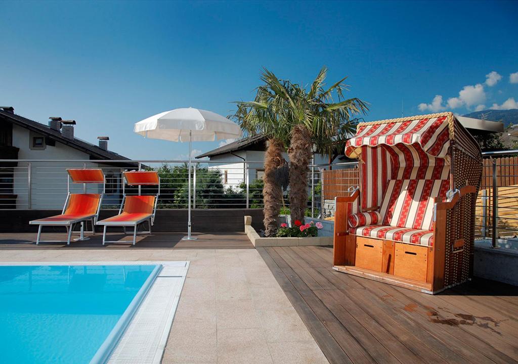 a patio with a pool and a chair and an umbrella at Hotel Garni Paler in Tirolo