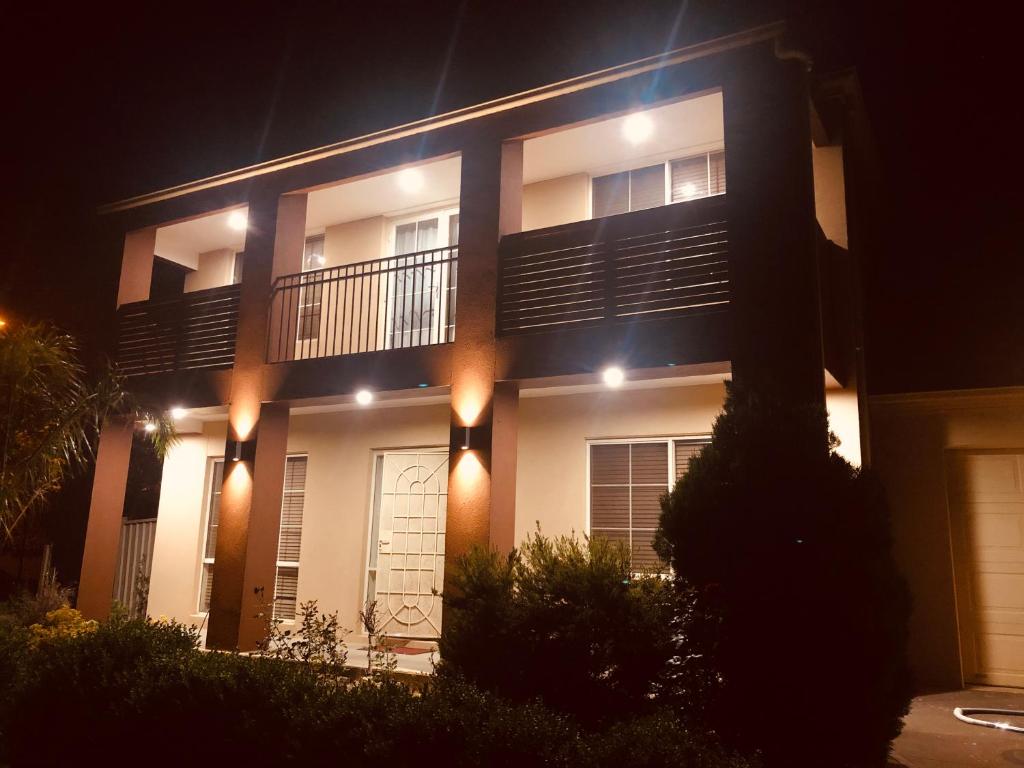 a large white building with a balcony at night at Golf View Charm in Craigieburn