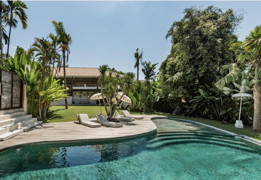 a swimming pool with lounge chairs and a house at La Payesa in Canggu