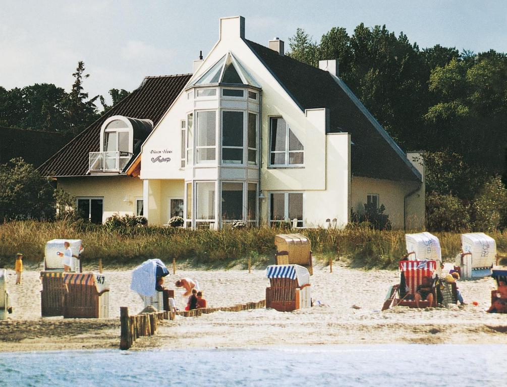 ein Haus am Strand mit Stühlen und Menschen am Sand in der Unterkunft Ferienwohnanlage Dünenhaus in Hohwacht