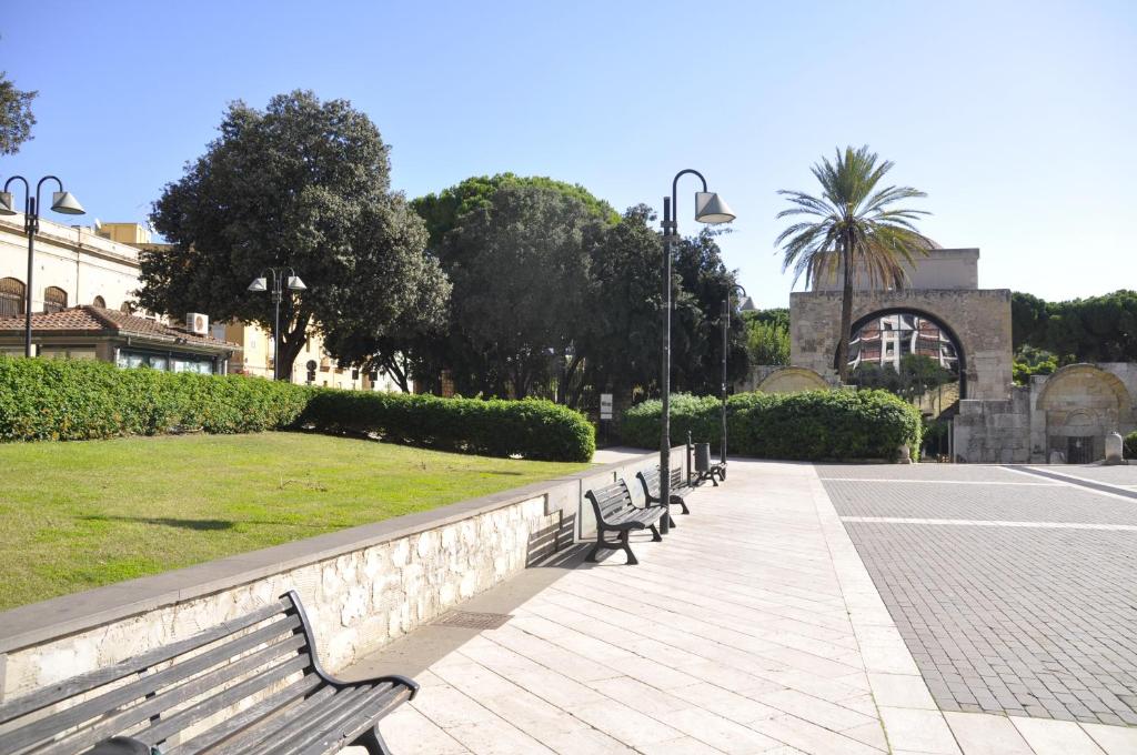 une rangée de bancs de parc sur un trottoir dans l'établissement Bed and Breakfast San Saturnino, à Cagliari