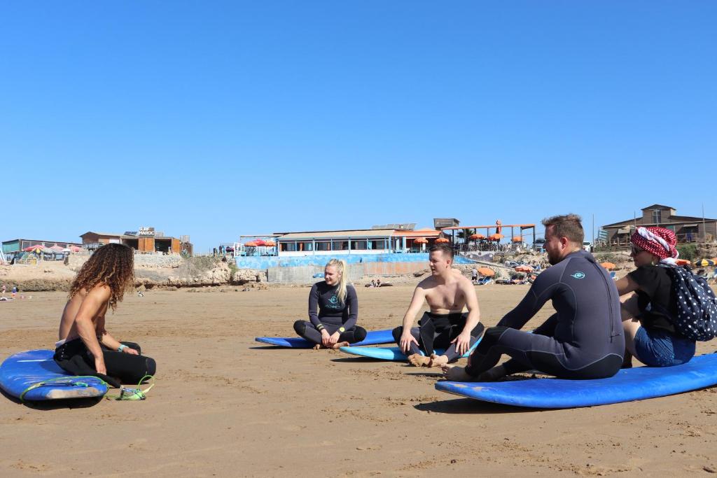 a group of people sitting on surfboards on the beach at Pearl Surf Camp Morocco in Agadir