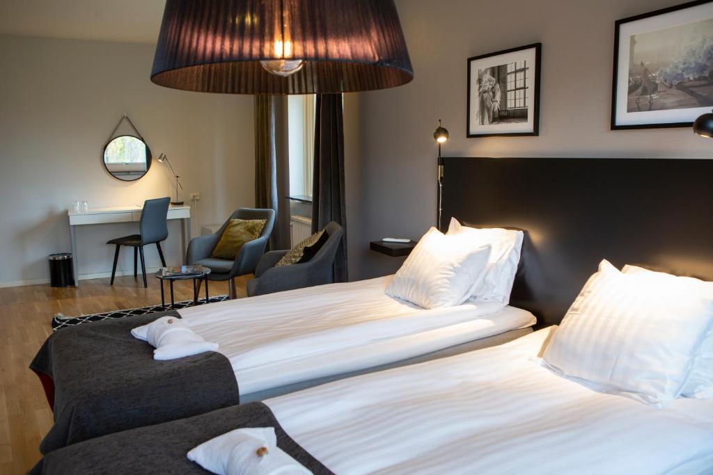 Cette chambre comprend deux lits et un bureau. dans l'établissement Hotell Solhem Park, à Borås