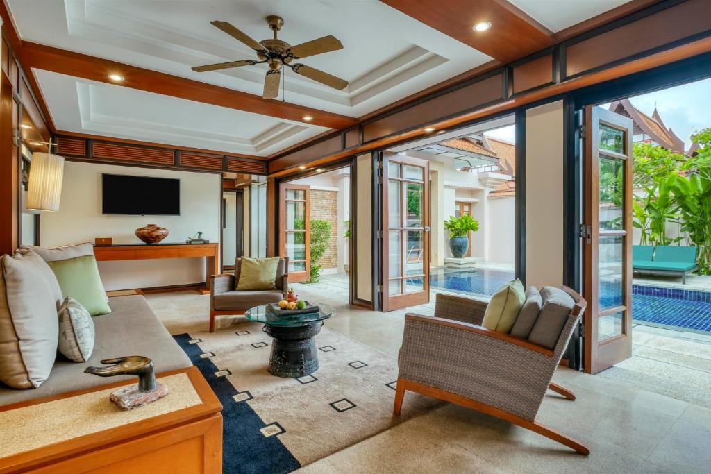 a living room with a ceiling fan and sliding glass doors at Banyan Tree Phuket in Bang Tao Beach