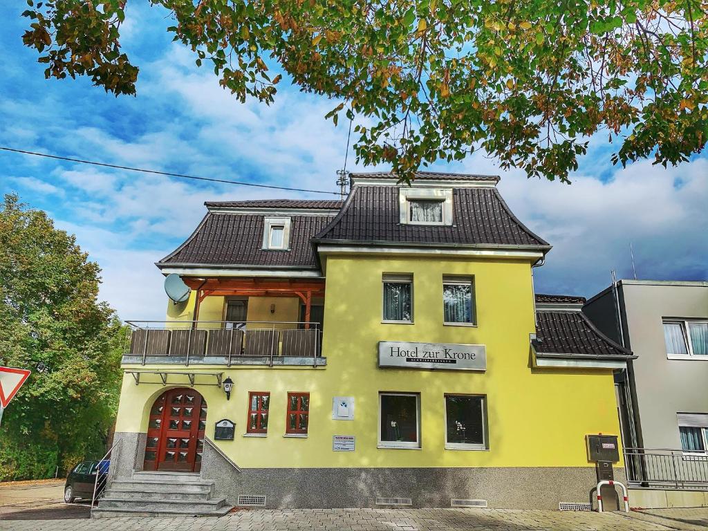 ein gelbes Gebäude mit schwarzem Dach in der Unterkunft Garni-Hotel zur Krone in Schwieberdingen