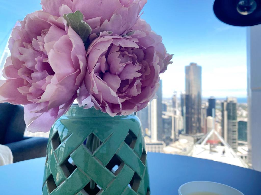 a vase with pink flowers sitting on a table at CBD Fabulous View 2BR high in the sky on Collins in Melbourne