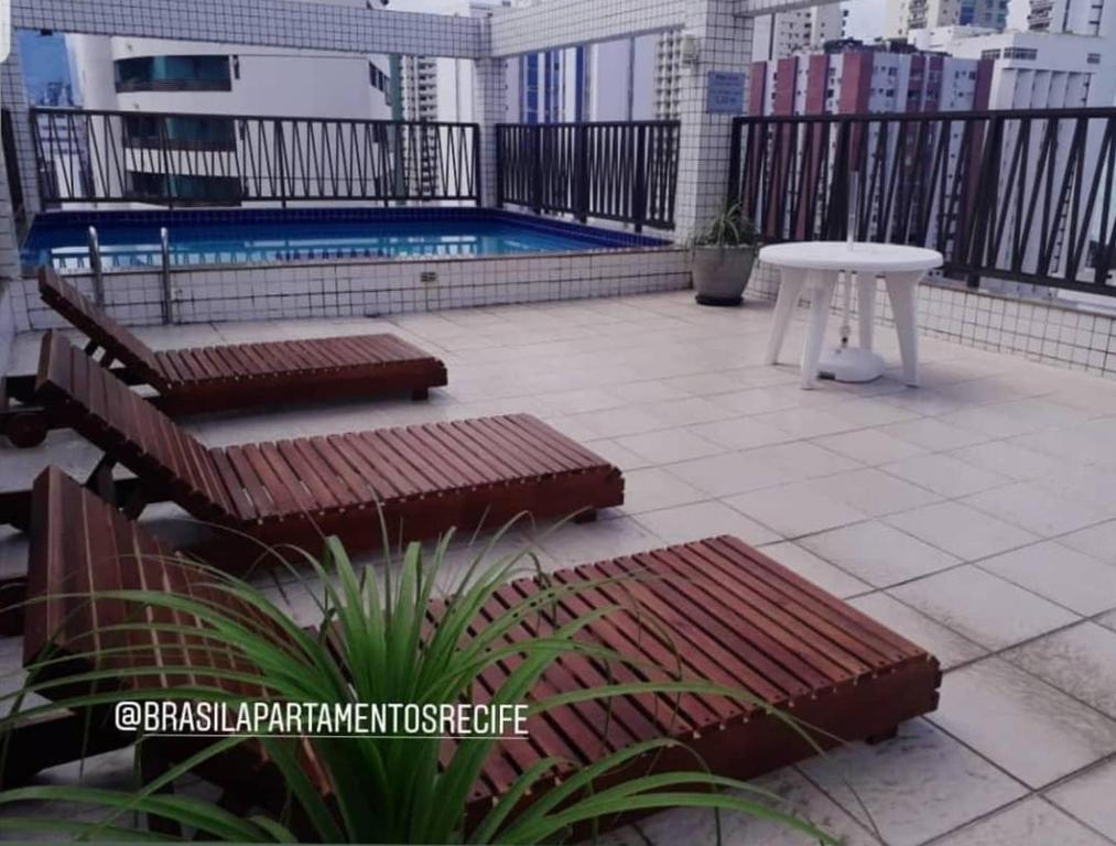 un patio con bancos, una mesa y una piscina en Boa Viagem Beach Flat apt 304, en Recife