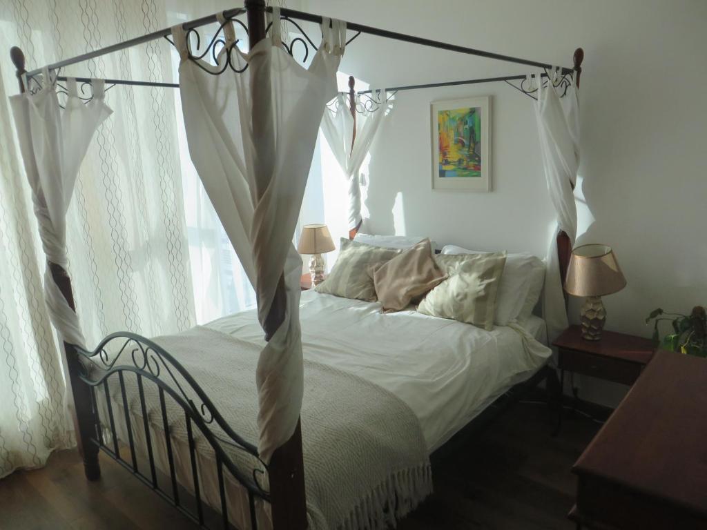 a bedroom with a canopy bed with white sheets and pillows at Studio Apartment - Skycourts in Dubai