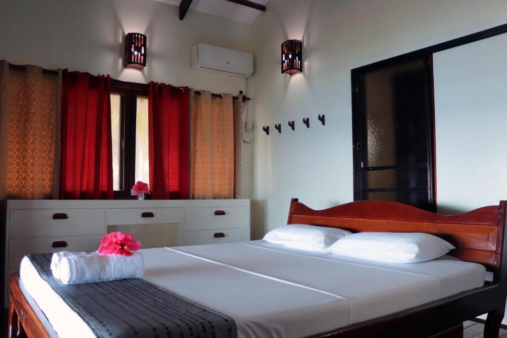 a bedroom with a large bed with red curtains at Siargao Sunrise Villa in General Luna