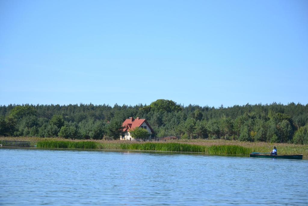 un hombre está en un barco en un lago en Zagajnik Holiday House, en Sucha Rzeczka