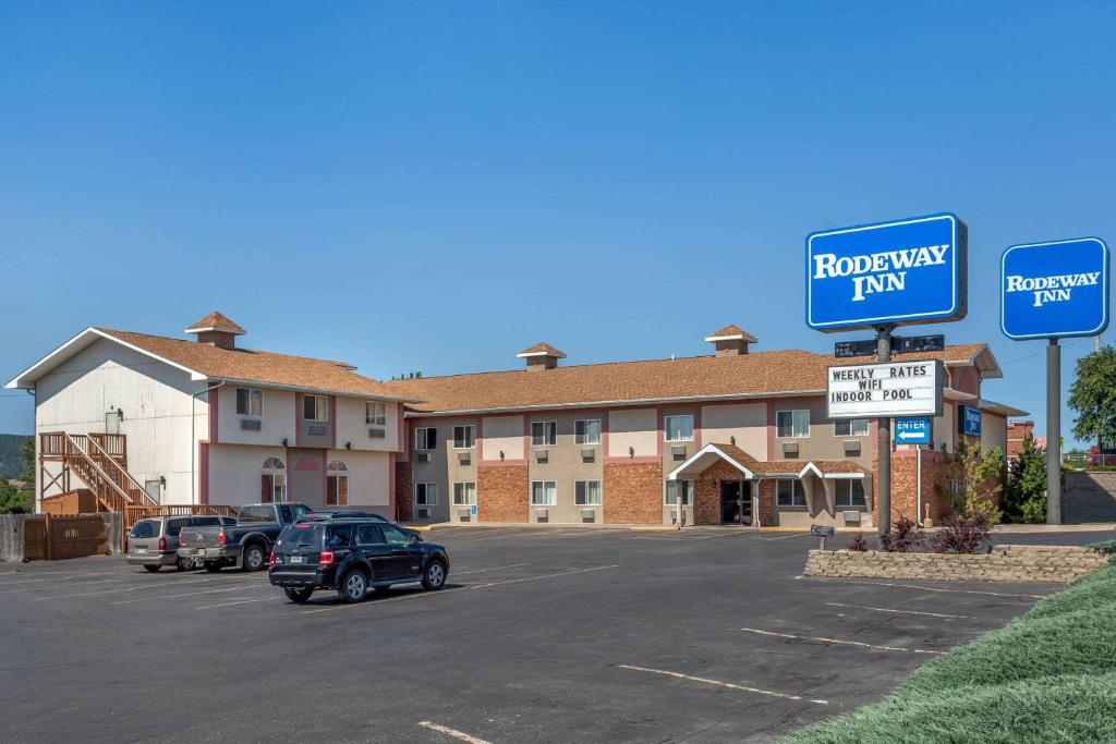 een hotel met auto's geparkeerd op een parkeerplaats bij Rodeway Inn Rapid City in Rapid City
