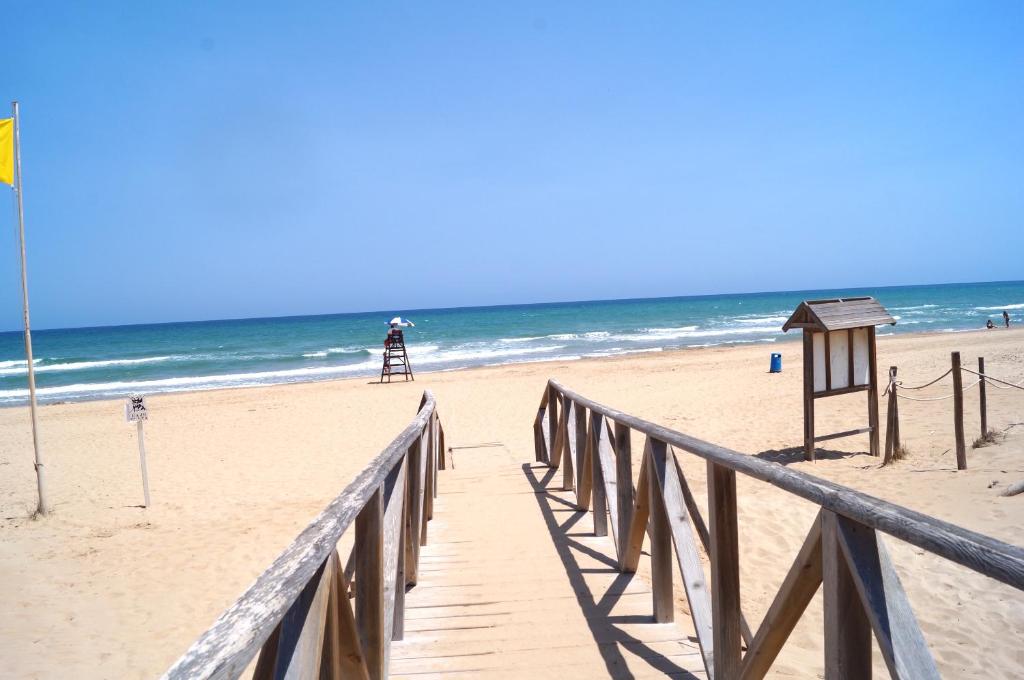 a wooden boardwalk leading to a beach with a lighthouse at ESPAGNE - ALICANTE - GUARDAMAR DEL SEGURA in Guardamar del Segura