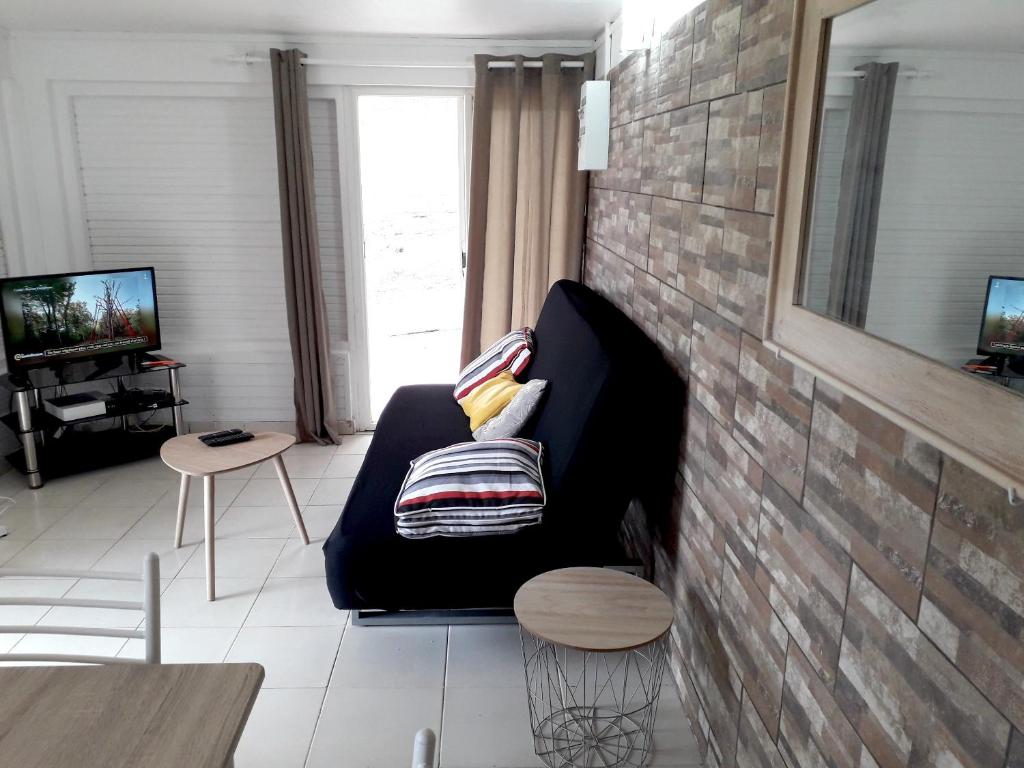 sala de estar con sofá y TV en Appartement de 2 chambres avec jardin clos et wifi a Saint Joseph a 7 km de la plage, en Saint-Joseph