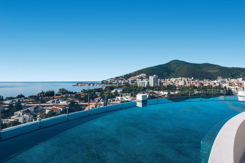 a swimming pool on the roof of a building with a city at Iberostar Waves Slavija in Budva