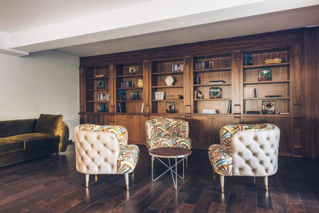 a living room with two chairs and a book shelf at Iberostar Waves Slavija in Budva