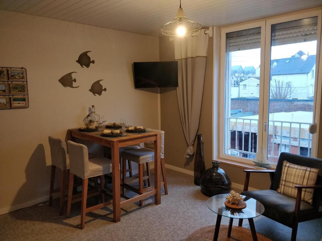 a living room with a table and a window at LES JACINTHES in Berck-sur-Mer