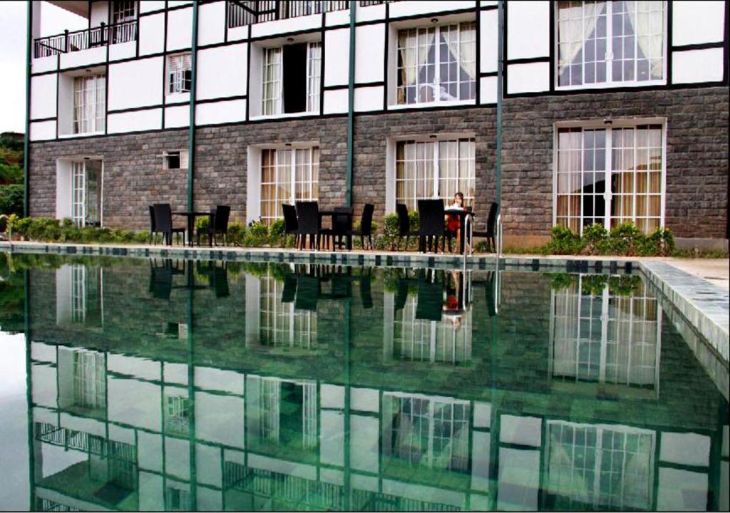 a person sitting at a table in front of a building at The Blackpool Resort & Spa in Nuwara Eliya