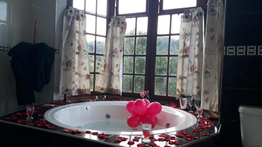 uma casa de banho com uma banheira com um laço rosa em Refúgio Serra Negra em Serra Negra