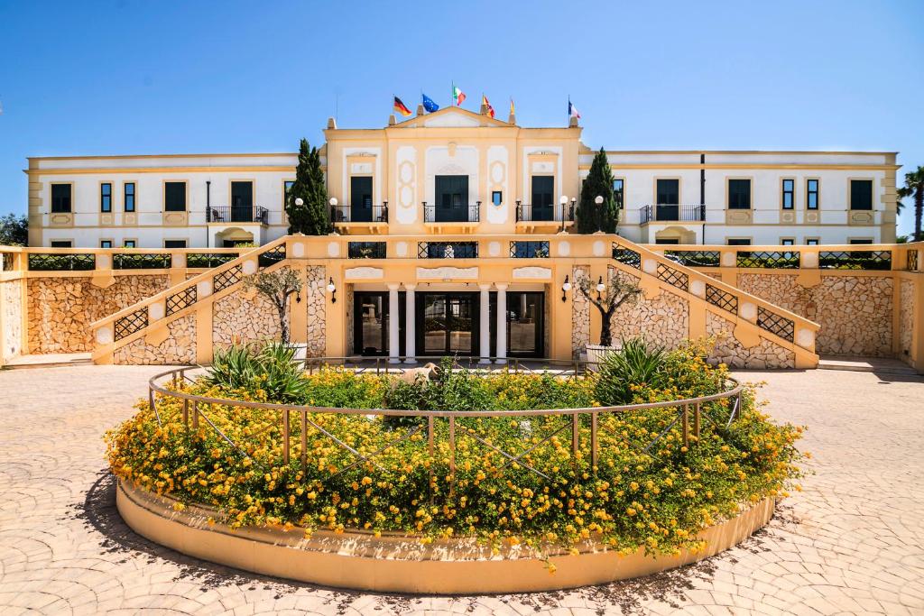 a building with a flower bed in front of it at Delfino Beach Hotel in Marsala