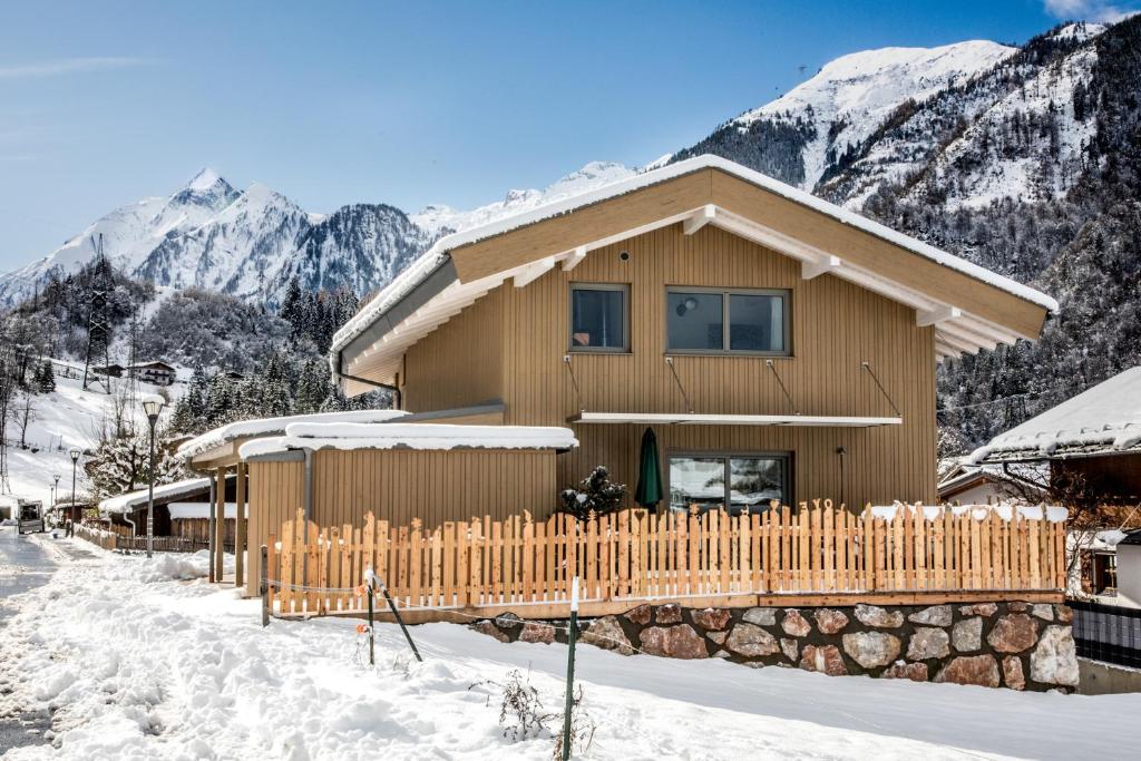 une maison en bois avec une clôture dans la neige dans l'établissement Haus Lukic, à Kaprun