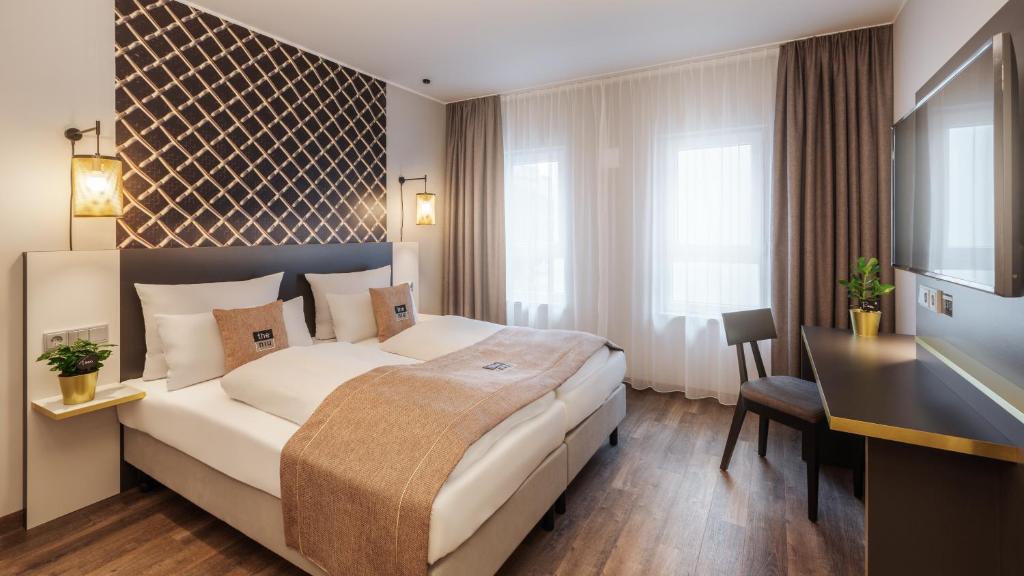ein Hotelzimmer mit einem großen Bett und einem Schreibtisch in der Unterkunft the niu Mesh in Stuttgart