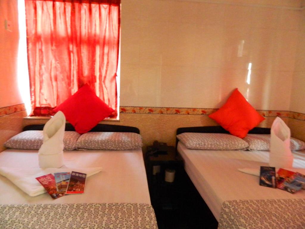 due letti in una stanza con cuscini rossi sopra di New London Hostel a Hong Kong