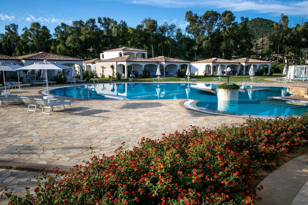 une grande piscine avec une maison en arrière-plan dans l'établissement Limone Beach Resort, à Castiadas