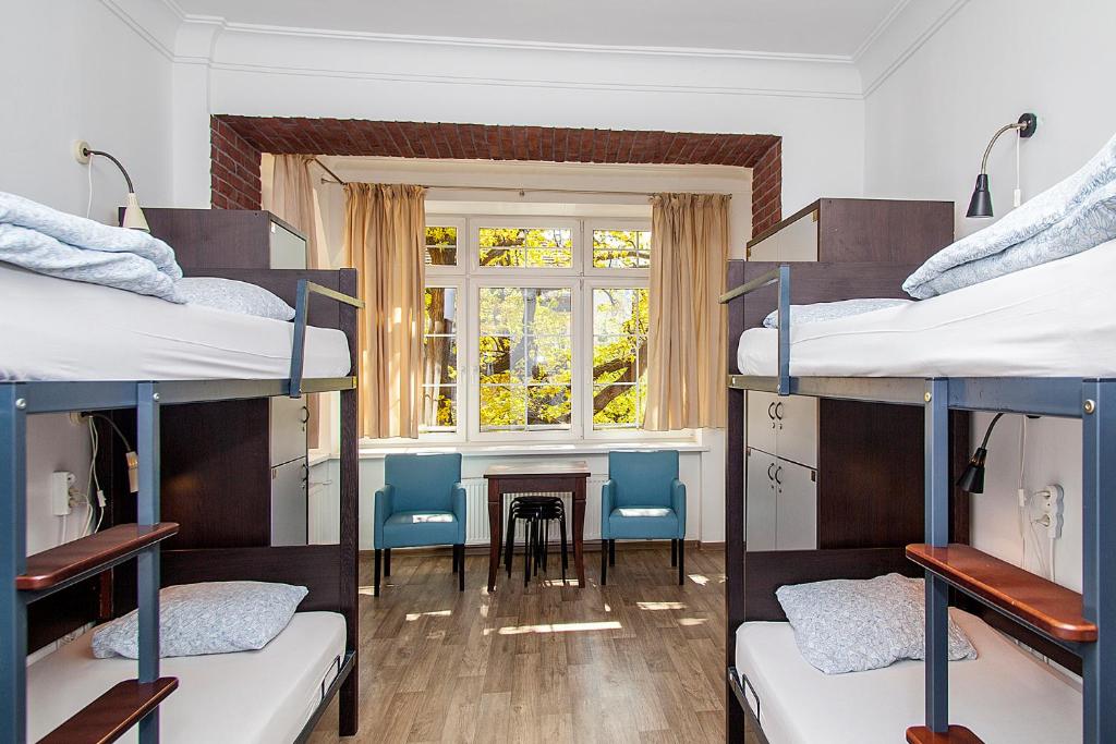 Ce dortoir comprend des lits superposés, une table et des chaises. dans l'établissement Hostel Wratislavia, à Wrocław