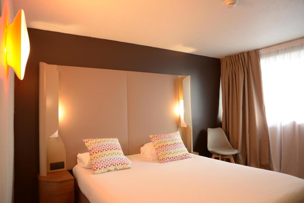 a bedroom with a white bed with pillows and a window at Campanile SETE - Balaruc in Balaruc-le-Vieux