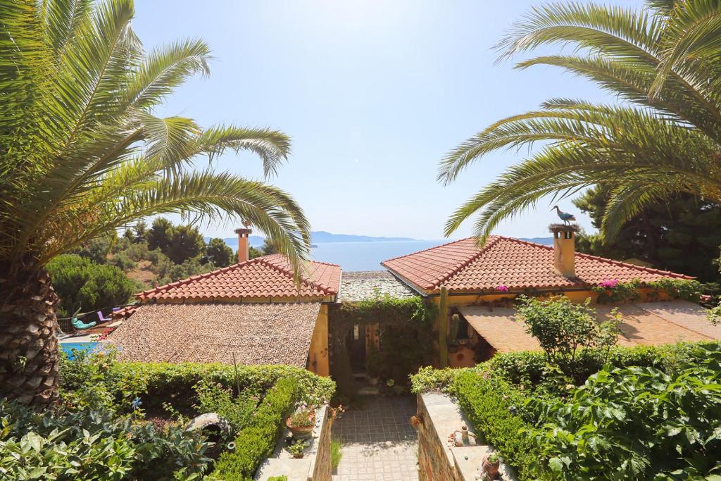 Absolute vacation luxury Villa Stratos near sea majestic view في Achladies: منزل به أشجار نخيل أمام المحيط