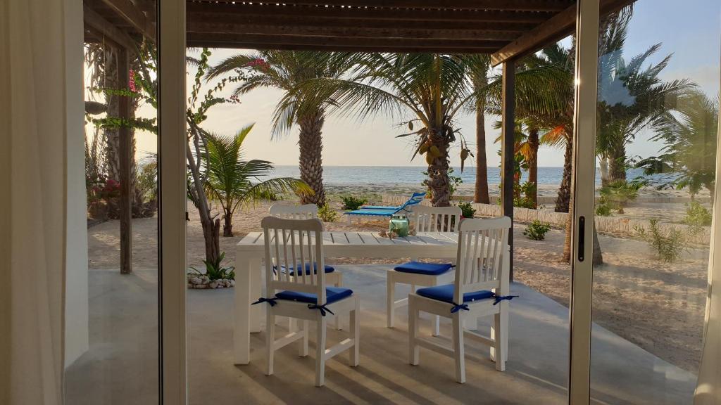 Beachhaus Praia de Chaves في Cabeçadas: شرفة مع كرسيين وطاولة على الشاطئ