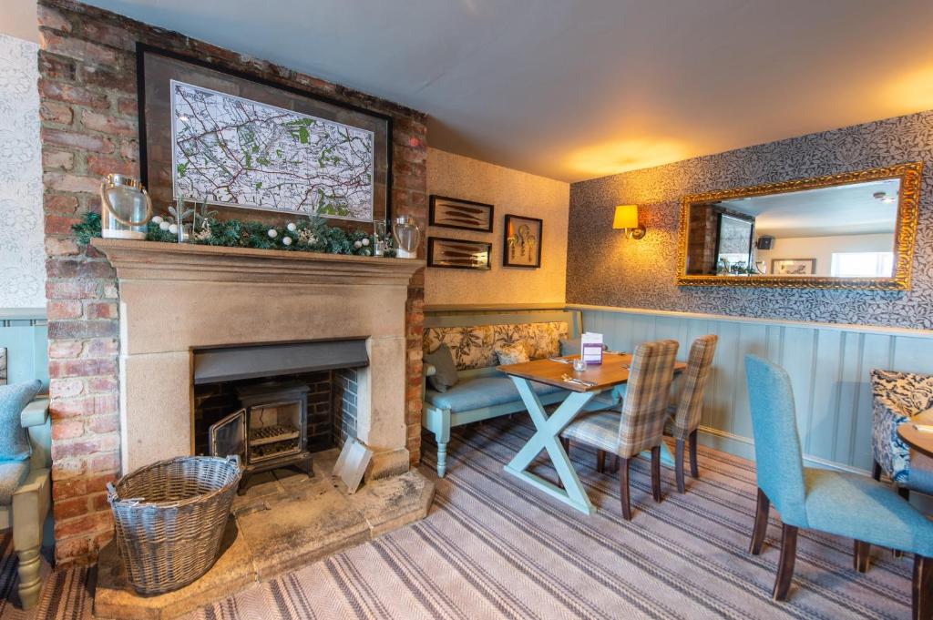 a living room with a fireplace and a table and chairs at Cross Keys by Chef & Brewer Collection in Nunthorpe