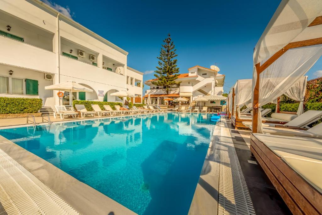 a swimming pool with chairs and a building at Chandris Apartments in Kavos