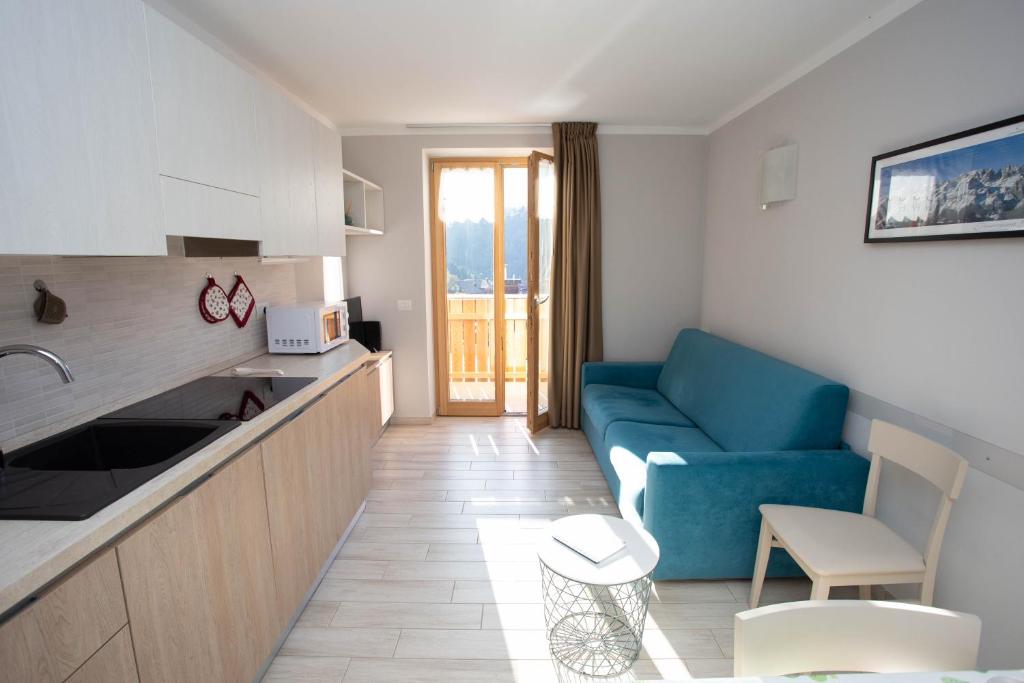 un soggiorno con divano blu e una cucina di Perla delle Dolomiti ad Andalo